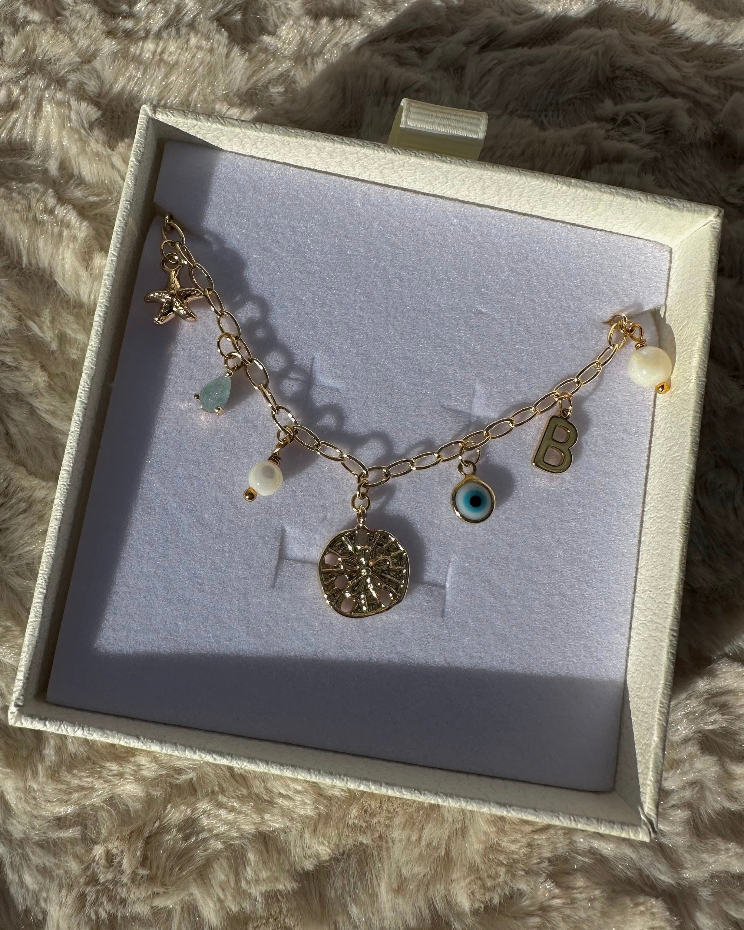 Bracelet with charms in a box on a fluffy surface
