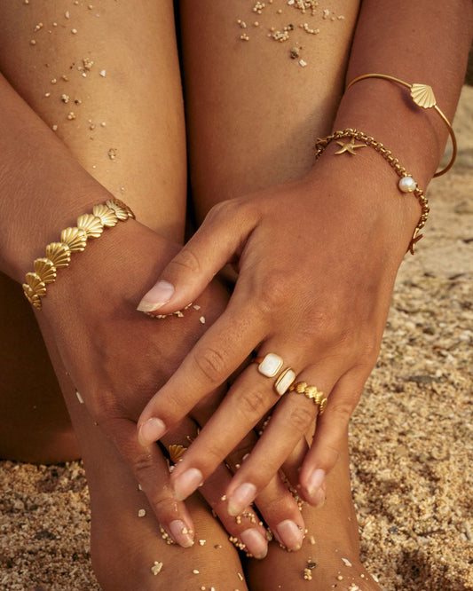 beeachy gold jewelry stack with chunky and dainty Shell Bracelet Cuffs, a charm bracelet and mathcing rings - Haylo & Co.