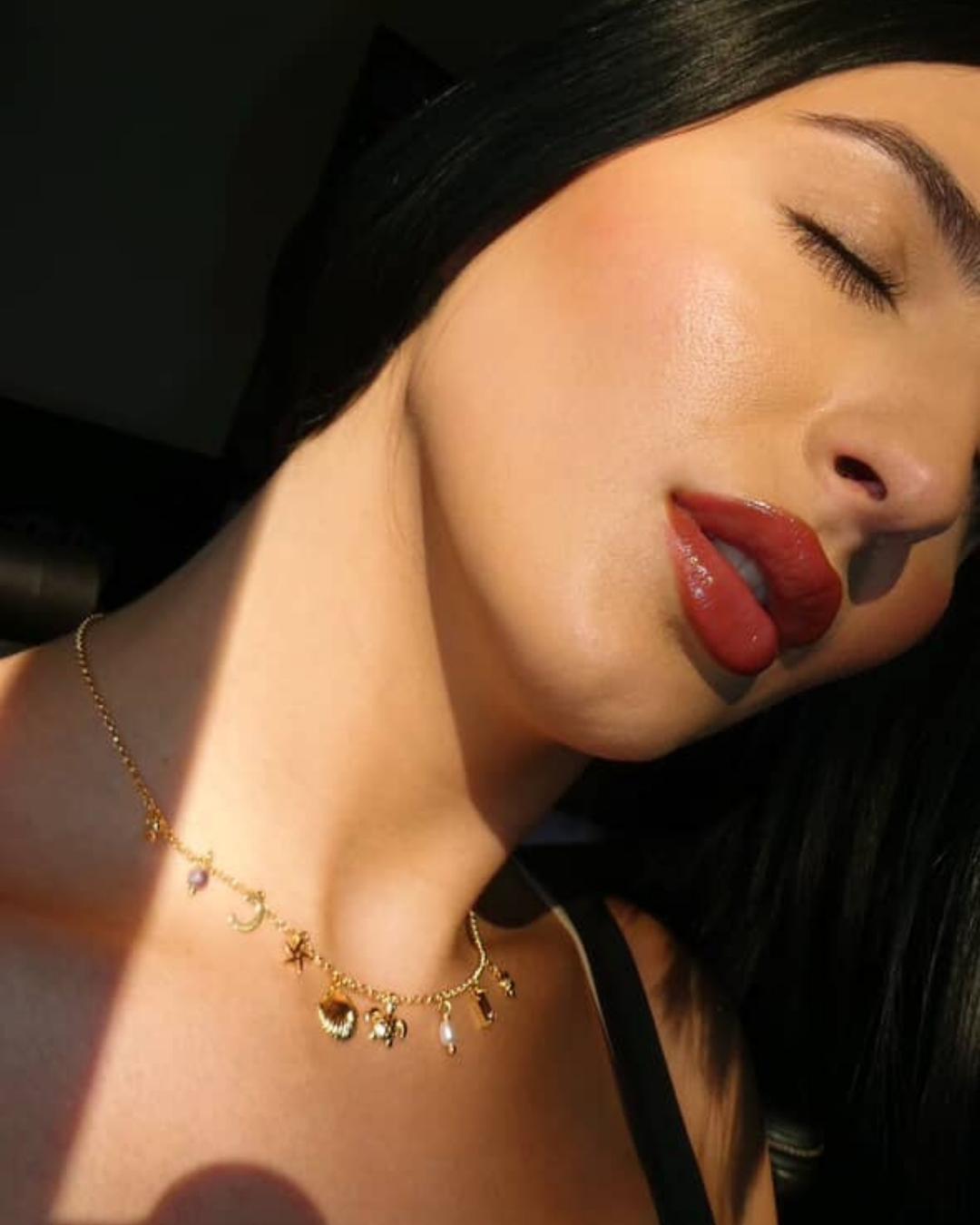 woman wearing a dainty gold charm necklace