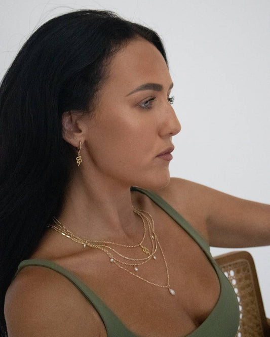 Woman wearing gold snake necklaces and earrings