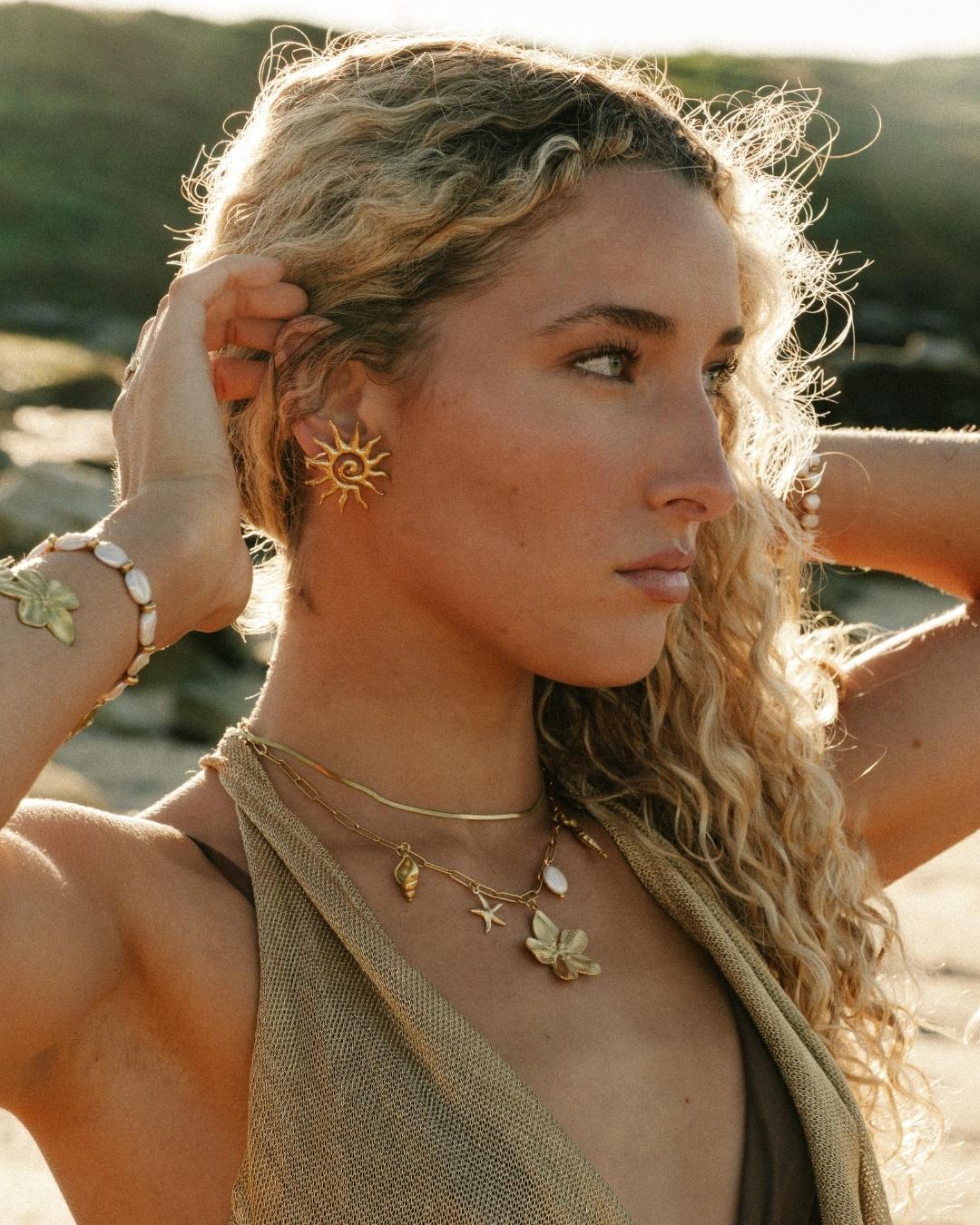 woman wearing gold jewelry stack with earrings, necklaces and bracelets