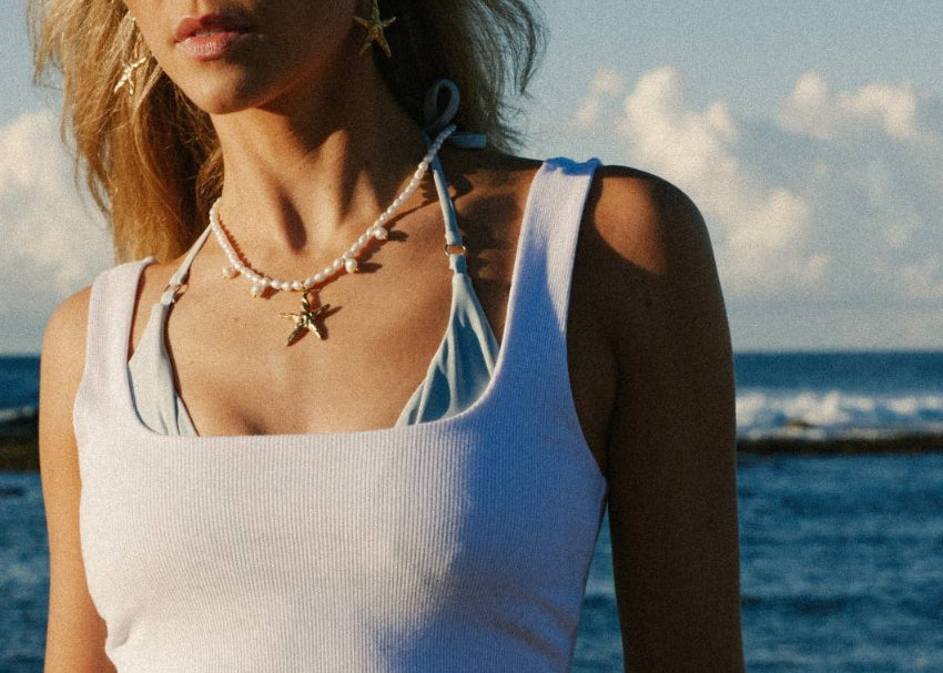 Woman wearing a white top and pearl necklace at the beach